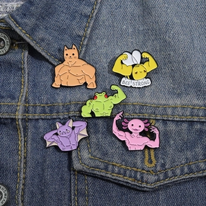 Detail of creative muscle animal enamel pins on blue denim fabric background