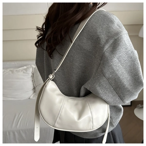 Detailed view of a white PU leather crescent bag worn by a model for size perspective