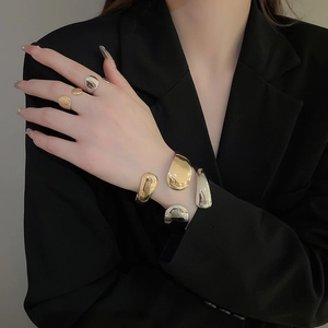 Detail of irregular organic gold and silver bracelets with a polished mirror finish