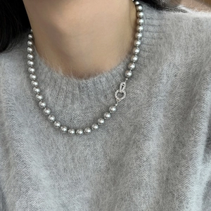Close-up of vintage grey pearl necklace with a diamond-encrusted silver clasp on a grey sweater
