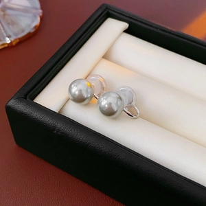 Detailed macro view of silver grey pearl clip earrings on white velvet jewelry box
