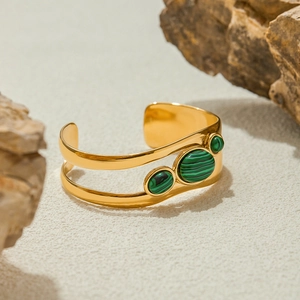 Detailed close-up of a gold-plated stainless steel cuff featuring three green stones