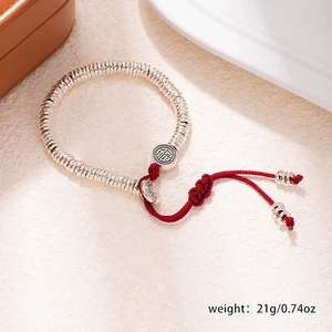 Detail of silver beaded bracelet with red braided cord and Fu character charm