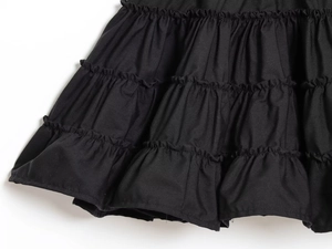 Macro shot of multi-layered pleated black skirt hem showcasing fine cotton texture