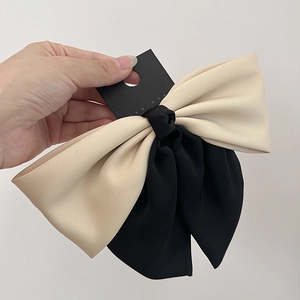 Detail of two-tone cream and black bow hair clip with high-quality matte fabric