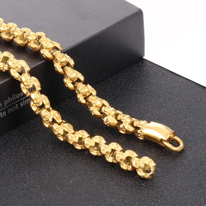 Macro detail of gothic gold-plated skull chain featuring heavy spring clasp links