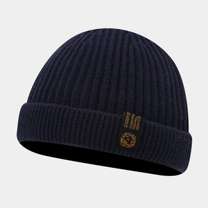 Détail d'un bonnet en maille côtelée bleu marine avec une étiquette textile noire cousue