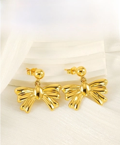 Detail of gold bow earrings featuring glossy metallic finish and 3D textured folds