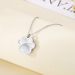 Macro view of silver paw pendant with white shell inlay and polished metal finish
