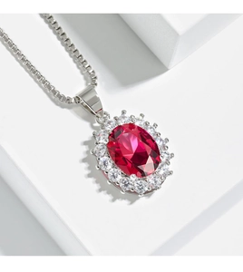 Macro detail of oval red gemstone necklace with diamond halo and silver box chain
