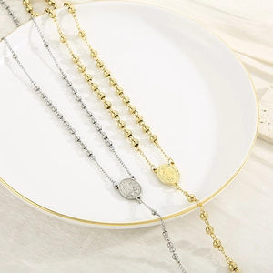 Flat lay of vintage stainless steel bead necklaces with religious saint medallions