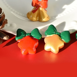 Close-up of festive red and gold resin Christmas bells with green bows on a holiday background