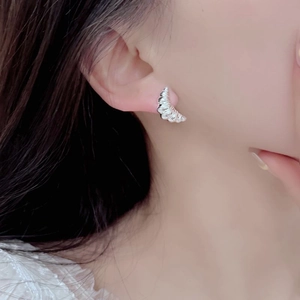 Macro view of S925 sterling silver croissant stud earrings worn for texture detail
