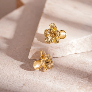 Elegant gold flower stud earrings with resin stones on a premium stone textured surface