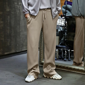 Detail of light brown pleated fabric texture and drawstring on men's wide-leg pants