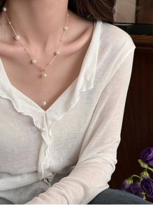 Detail of French vintage pearl Y-shaped necklace on model with white collar