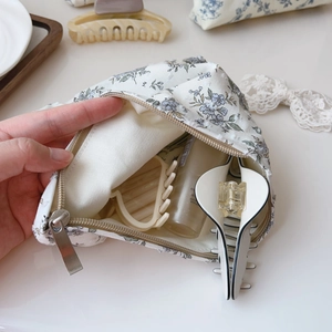 Detail of floral canvas makeup bag with blue flower print and smooth metal zipper closure