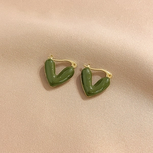 Elegant gold-plated V-shaped green enamel heart earrings on a beige silk background