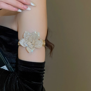 Detailed close-up of a luxury gold arm cuff featuring a sparkling rhinestone flower design