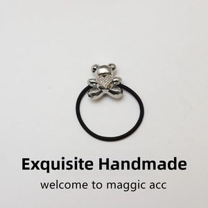 Detail of black elastic hair tie with silver teddy bear charm and crystal heart