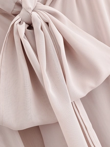 Detailed macro view of the bow-tie knot on a light pink chiffon evening dress