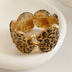Close-up of leopard print resin bracelet with gold metal spacer beads on a white tray