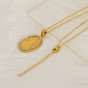Close-up of golden oval Virgin Mary pendant with sparkling white rhinestones on necklace