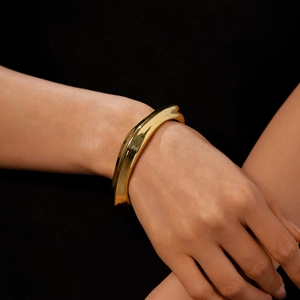 Polished gold irregular wave bangle with a metallic minimalist fluid design