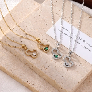 Colliers avec pendentifs en forme de gourde et cœur sertis d'émeraudes sur pierre beige