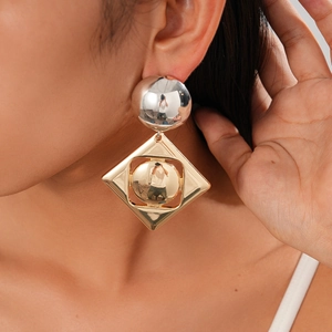 Detail of geometric metal earrings with silver spheres and golden diamond frames on model