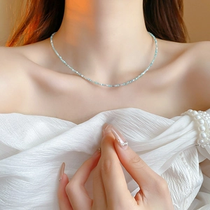 Close-up of elegant gold-plated geometric necklace with pale blue and green pearls