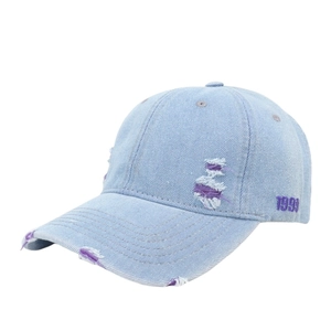 Detail of purple 1999 embroidery and distressed denim holes on light blue baseball cap
