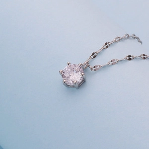 Macro shot of silver S925 necklace featuring a six-prong set round clear diamond pendant