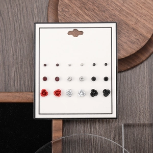 Close-up of 12 pairs of stud earrings featuring red roses and crystals on wood