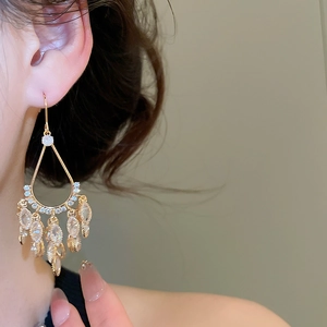 Close-up of gold plated teardrop tassel earrings with sparkling zircon stones