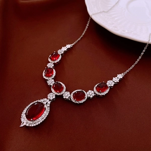 Macro shot of silver necklace featuring red oval gems and sparkling zircon stones