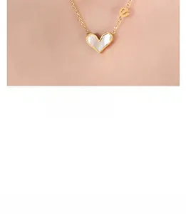 Detail view of heart-shaped white shell pendant with gold letter e on a fine chain