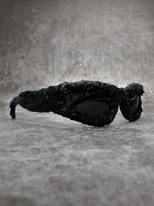 Detail view of avant-garde black oversized sunglasses with industrial textured coating