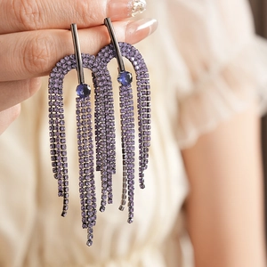 Detail of lavender purple rhinestone tassel earrings with blue stones on hand