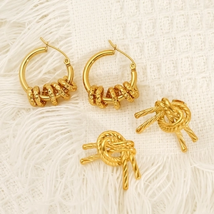 Golden woven knot earrings and hammered hoop sets on a textured minimalist background