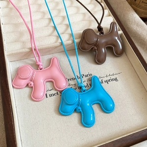 Détail de trois colliers chiots en résine rose, bleu et marron dans un coffret en velours