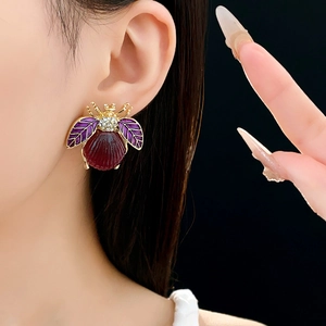 Detailed close-up of a vintage bee earring with purple enamel and sparkling crystals