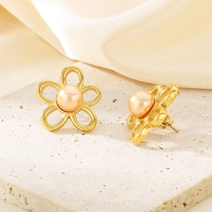 Detailed macro of gold flower stud earrings featuring orange pearls and filigree petals