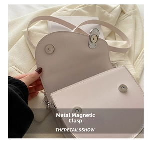 Detail showing dual silver magnetic buckles and smooth leather on a cream saddle bag