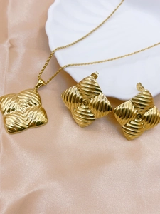 Detail of gold square necklace and earrings set with spiral ocean shell texture