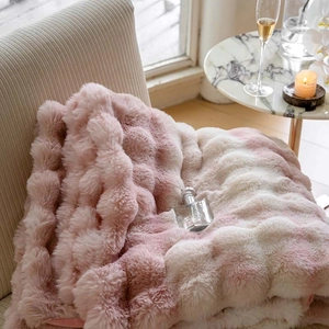 Detail of pink gradient faux fur blanket with bubble texture on a beige chair