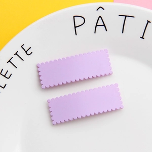 Dettaglio di due fermagli per capelli viola ondulati rettangolari su un piatto di ceramica