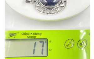 Detail view of a hexagram crystal necklace pendant weighing 17 grams on a scale.