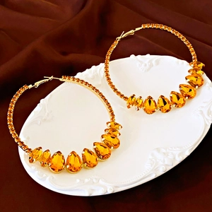 Chic oversized geometric hoop earrings with amber crystals and gold base on elegant tray