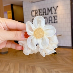 Detail of beige organza flower hair scrunchie with sparkling gold glitter center